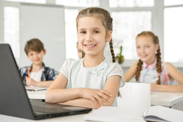 Fototapeta na wymiar Little cute girl using laptop at school lesson