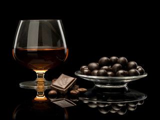 Cognac in glass and chocolate covered coffee beans