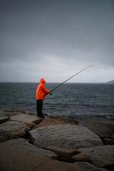 Fototapeta na wymiar fisherman with flashy raincoat fishing in the rain
