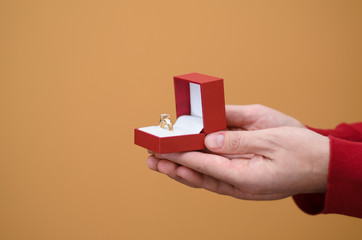 Man's hands holding an open red box with an engagement ring