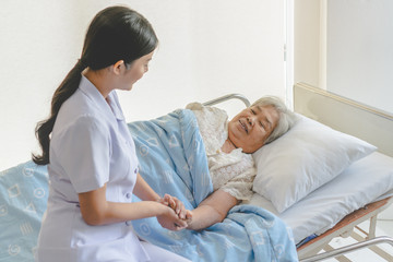 Obraz premium asian female home nursing holding hand of older lady on the bed and encouraging patient