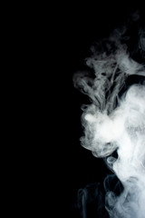 Сlouds of vape fog on black background. At right side thick smoke rising up. Vape culture and no smoking movement.