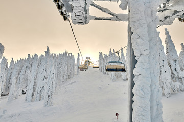 Chair lift in Poiana Brasov ski resort, Skiers and snowboarders enjoy the ski slopes in Poiana...