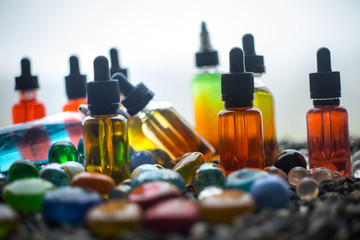 Vape concept. Beautiful colorful vape liquid glass bottles outdoor on stones. Useful as background...
