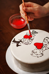 Confectioner makes illustration with icing on mousse cake. Gift for Valentine's Day. Homemade pastry shop.