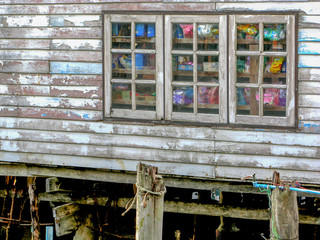 Old white wooden house in fisherman's village with lots of stuffs seen through the window.