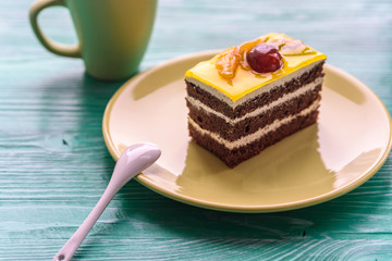 Chocolate puff cake with cherry on top and a cup of coffee photographed close-up on a wooden background.