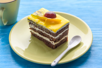 Chocolate puff cake with cherry on top and a cup of coffee photographed close-up on a wooden background.
