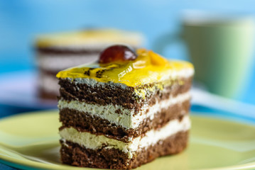 Chocolate puff cake with cherry on top and a cup of coffee photographed close-up on a wooden background.