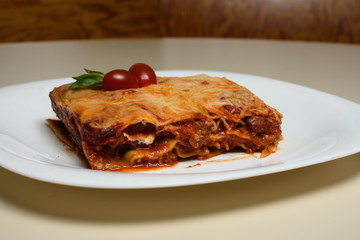 Lasaña de carne y tomates en plato blanco