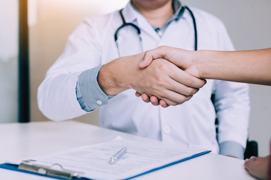 Doctor Shaking Hands With Older Patient In The Clinic Room.