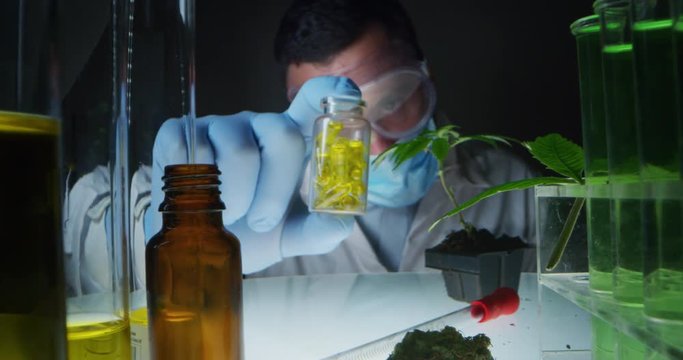Slow motion of a scientist showing a jar with capsules of biological and ecological hemp plant herbal pharmaceutical cbd oil in a laboratory.