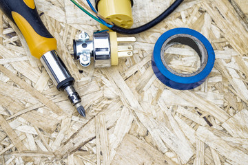 Screwdriver with wires, electrical tape and sockets on the background of OSB panel. The concept of...
