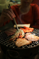 Grilling barbecue on mesh grill of charcoal fire. Korean or japanese traditional food grilling style barbecue.