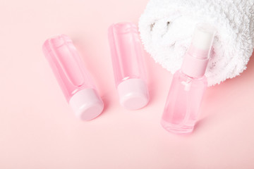 Three  bottles of tonic or lotion and white towel on pink or powder background. Freshness and body care. Female cosmetics. Micellar water. Travel set of face care cosmetic