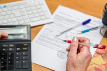 hand holds pen, office work, documents on the table, print, calculator and other office supplies