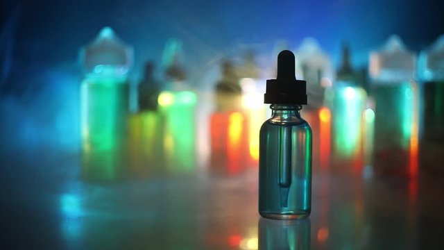 Vape concept. Smoke clouds and vape liquid bottles on dark background. Light effects. Useful as background or electronic cigarette advertisement. Selective focus