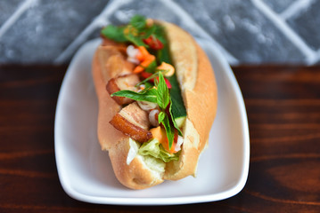 Delicious Vietnamese style hot dog bahn mi in a crusty baguette bun with pork, herbs, vegetables