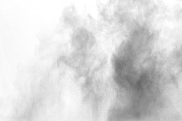 Black powder explosion against white background. Charcoal dust particles exhale in the air.