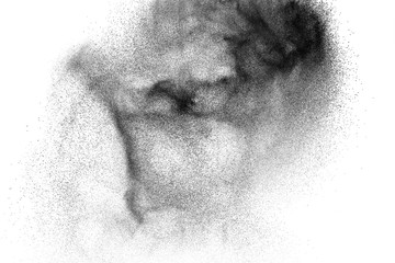 Black powder explosion against white background. Charcoal dust particles exhale in the air.