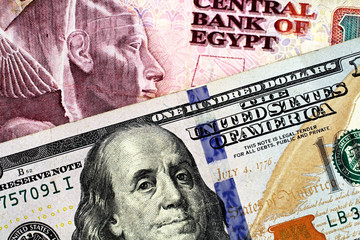 An Egyptian ten pound bank note with a blue American one hundred dollar bill