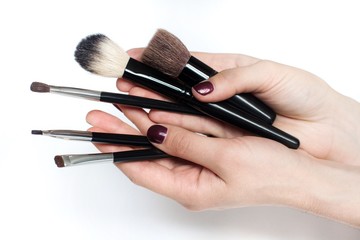 young woman holding black makeup brushes  on white background