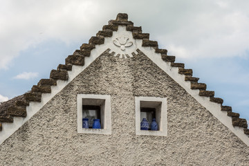 Top front of a traditional Hungarian house with traditional blue ceramic jars in the windows