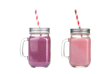 Fruit smoothies in glass jars on a white background.