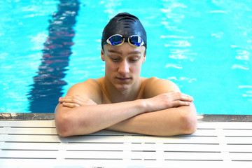 Portrait of a depressed swimmer on the background of the pool.