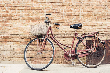 Old bicycle with a basket leaning against a wall 