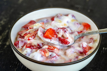 Red strawberry and white yogurt brulee. Fruit dessert on breakfast with wedges of perfectly ripe in season strawberry, closeup