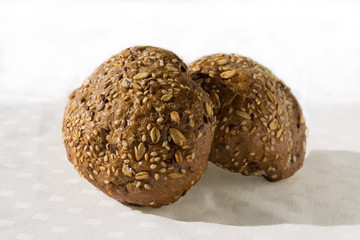 Twee round dark colored buns with varios seeds on a light background. Close up. Buns for a breakfast, filling, dessert