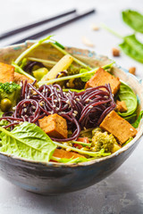Vegan black rice noodles with tofu and vegetables, white background.