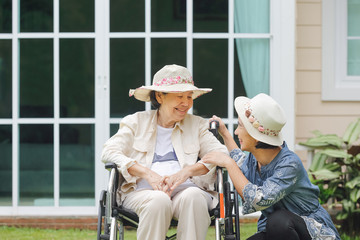 Fototapeta na wymiar Elderly woman relax on wheelchair in backyard with daughter