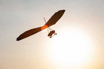 Hang-glider silhouette in sky in sunset time