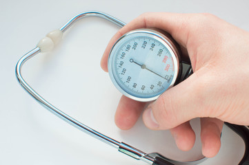 A doctor demonstrates a sphygmomanometer. A hand is holding a pressure meter