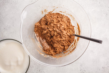 Cooking vegan chocolate cake with aquafaba in glass bowl, top view.