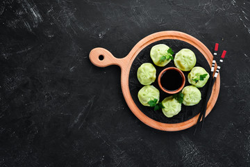 Hinkali with meat, spinach and soy sauce. On a black background. Top view. Free copy space.