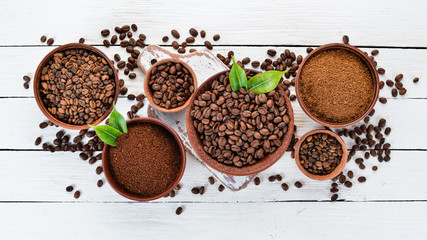 Ground coffee and coffee beans. On a white wooden background. Top view. Free space for your text.