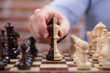 Person's Hand Moving A King Chess Piece