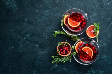 Hot tea with berry cranberry and orange. On the black kitchen background. Top view. Free space for your text.