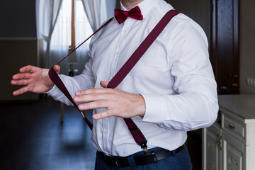 Naklejka premium the groom holds his hands suspenders in a suit