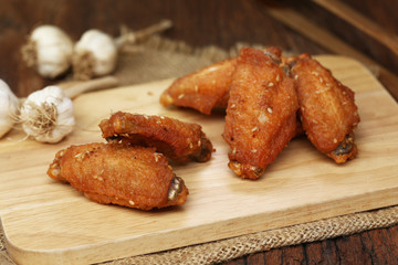Beautiful plate fried chicken wings on wooden tray with garlic and pepper, selective focus and free copy space. Clean food good taste concept.