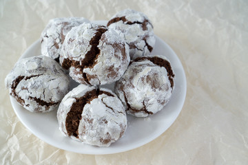 Сracked chocolate cookies in icing sugar on a white plate with copy space