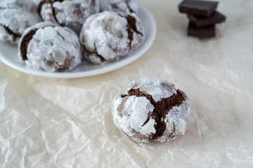 Сracked chocolate cookies in icing sugar on a white plate with copy space