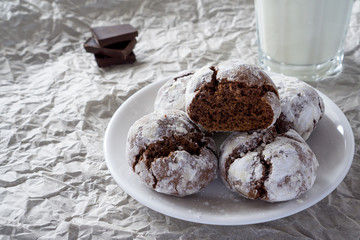 Сracked chocolate cookies in icing sugar on a white plate with copy space