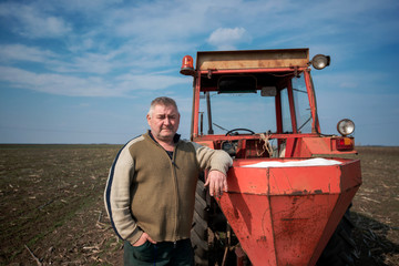 Portrait farmer leaning on tractor. Concept of agriculture and field works.