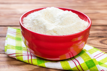 Bowl with grated parmesan on wooden table.