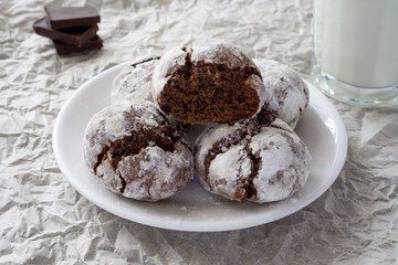 Сracked chocolate cookies in icing sugar on a white plate with copy space