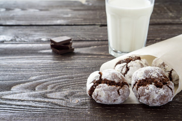 Сracked chocolate cookies in icing sugar on a white plate with copy space